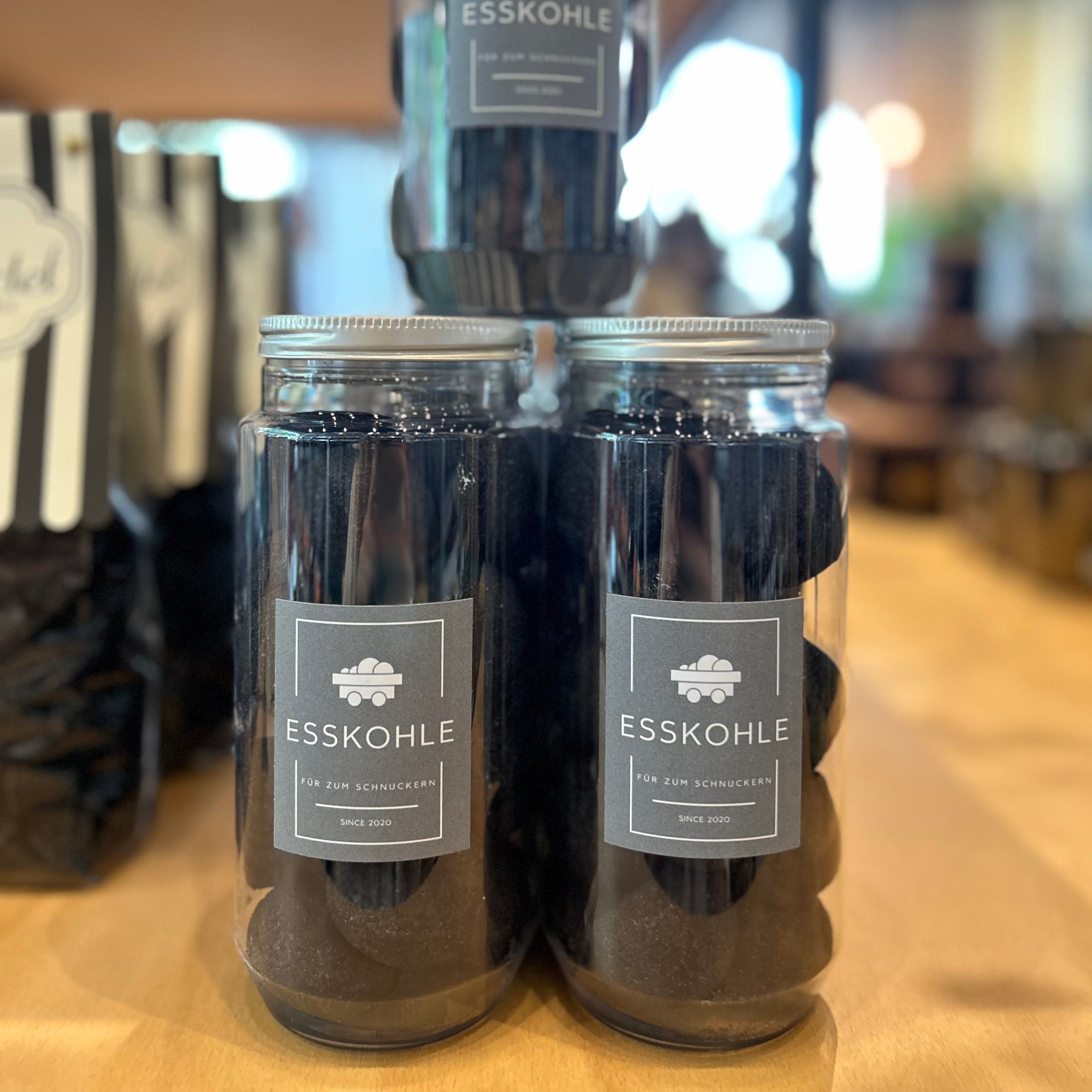 Esskohle Süßigkeit im 150g PET-Glas – originelle Geschenkidee aus dem Ruhrgebiet. Schwarze Süßwaren in Kohle-Optik mit Etikett ‚Esskohle – Für zum Schnuckern, Since 2020‘, ideal als Mitbringsel oder Ruhrpott-Souvenir.