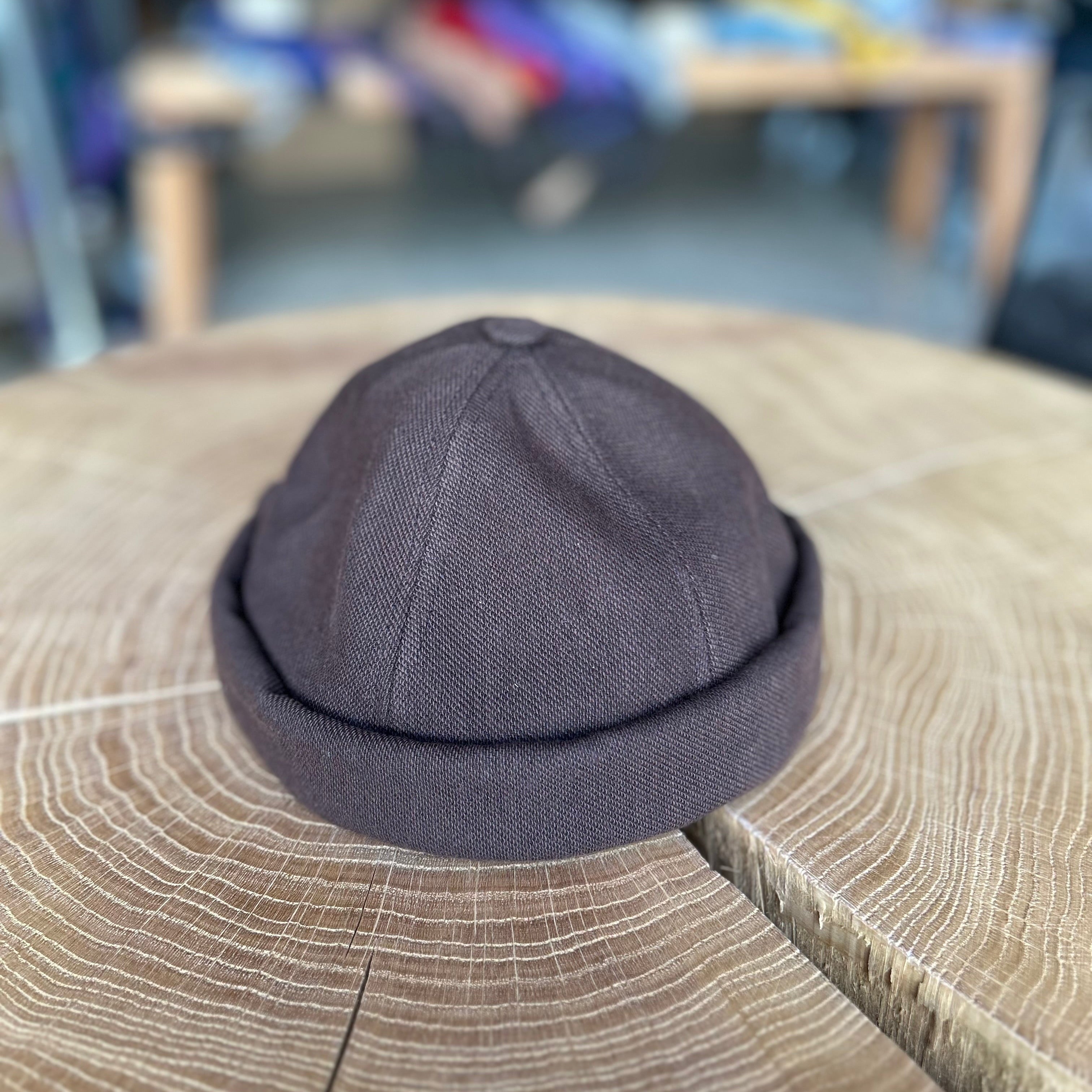 Fischermütze in der Farbe Braun, liegt auf einem Holztisch
