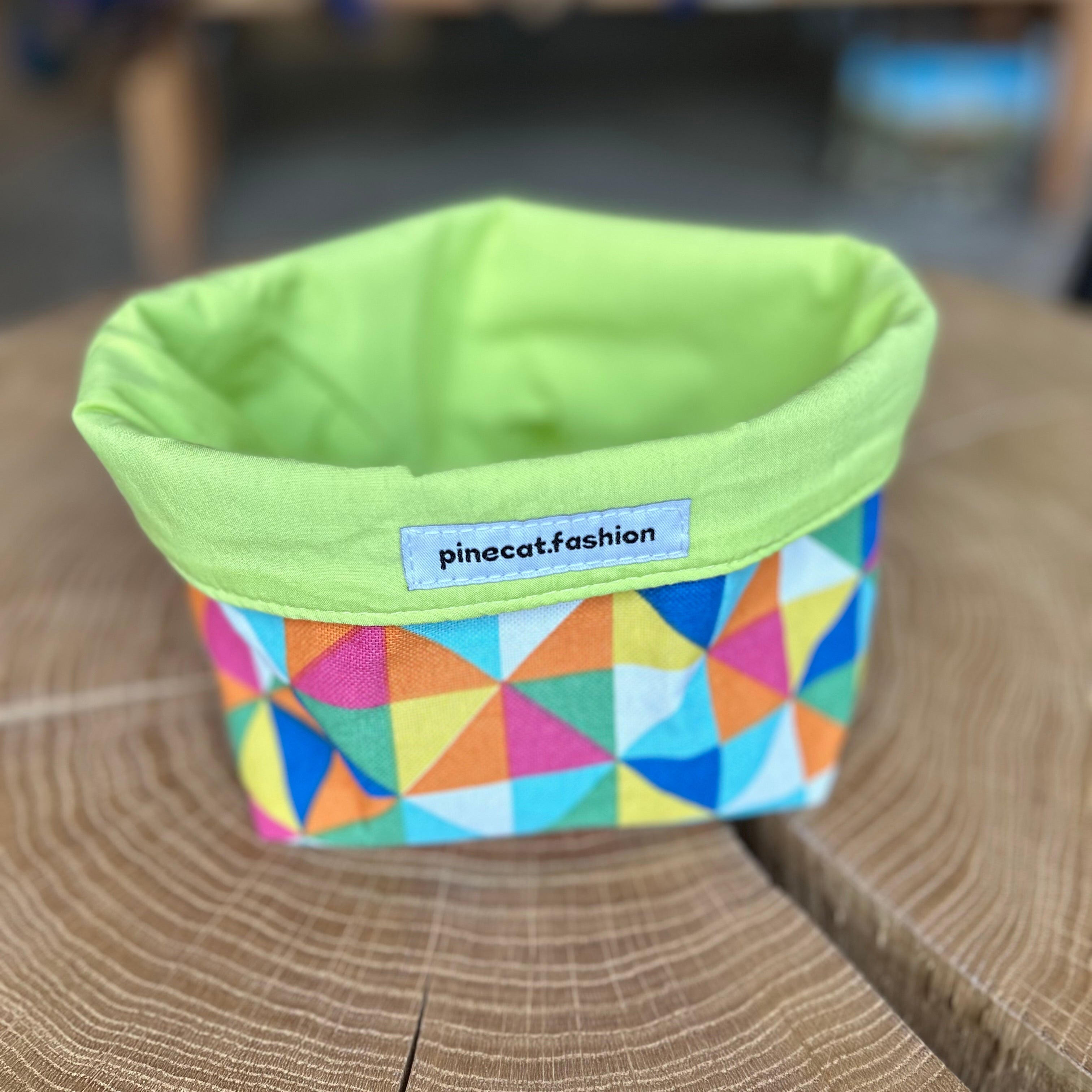 Pinecat Körbchen Neon-Grün liegt auf einem Holztisch