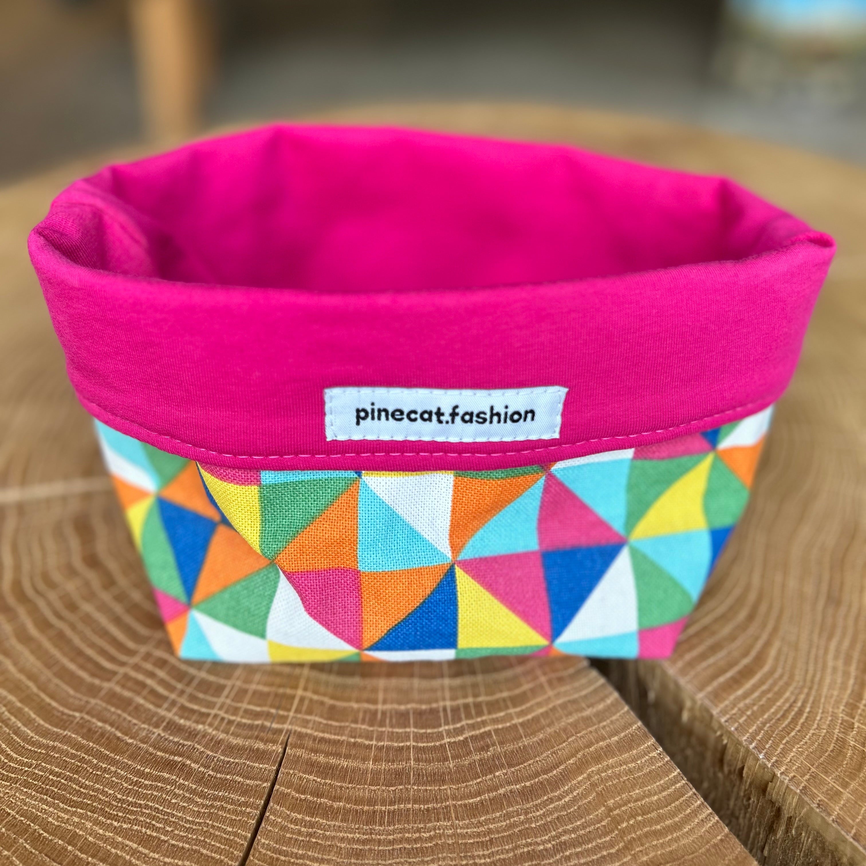 Pinecat Körbchen Pink-Bunt liegt auf einem Holztisch
