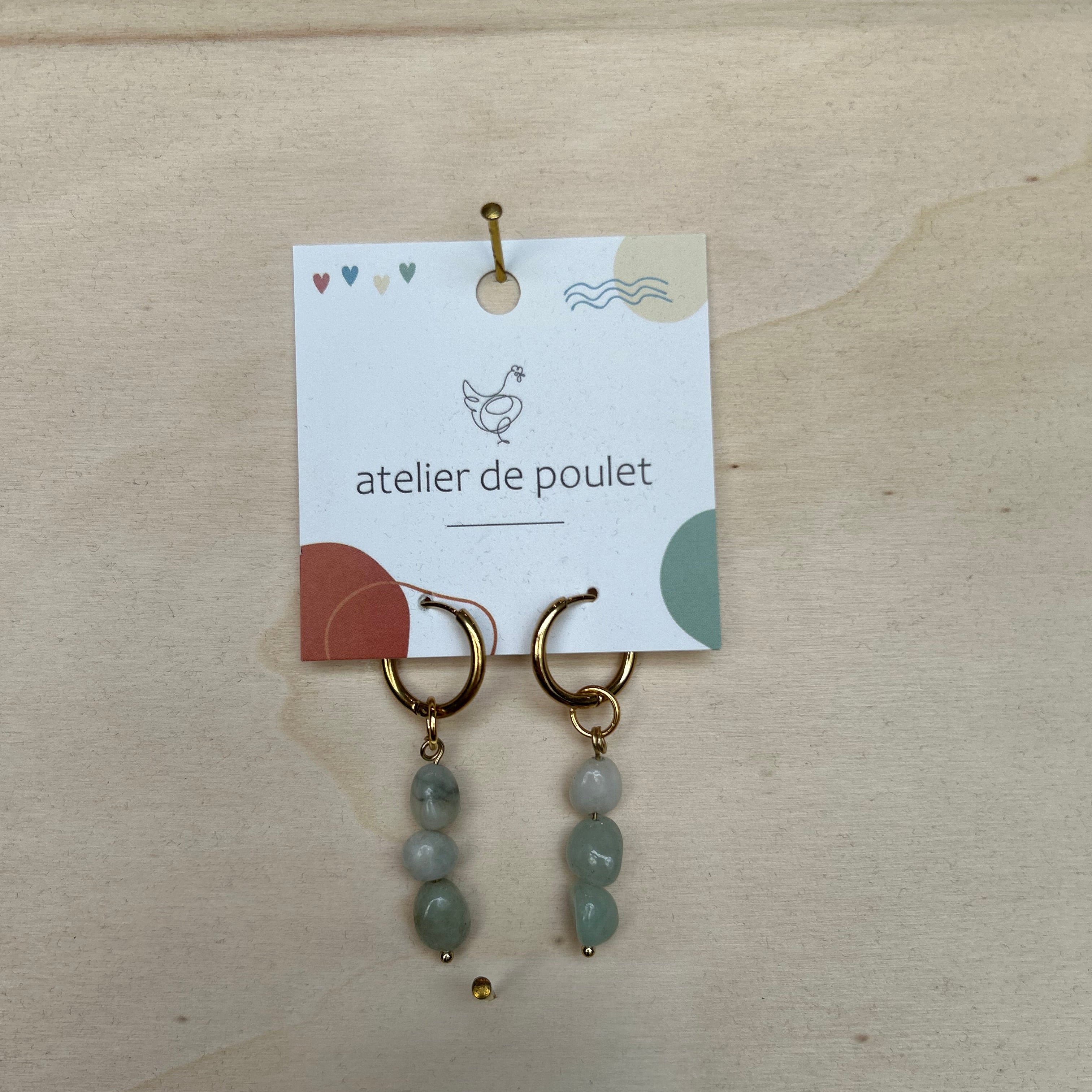 „Handgemachte Ohrringe von atelier de poulet – aus Edelsteinen in der Farbe Hell-Blau, präsentiert auf Holzdisplay. Stilvolle Damen-Ohrringe als individueller Modeschmuck, ideal als Geschenk oder Accessoire