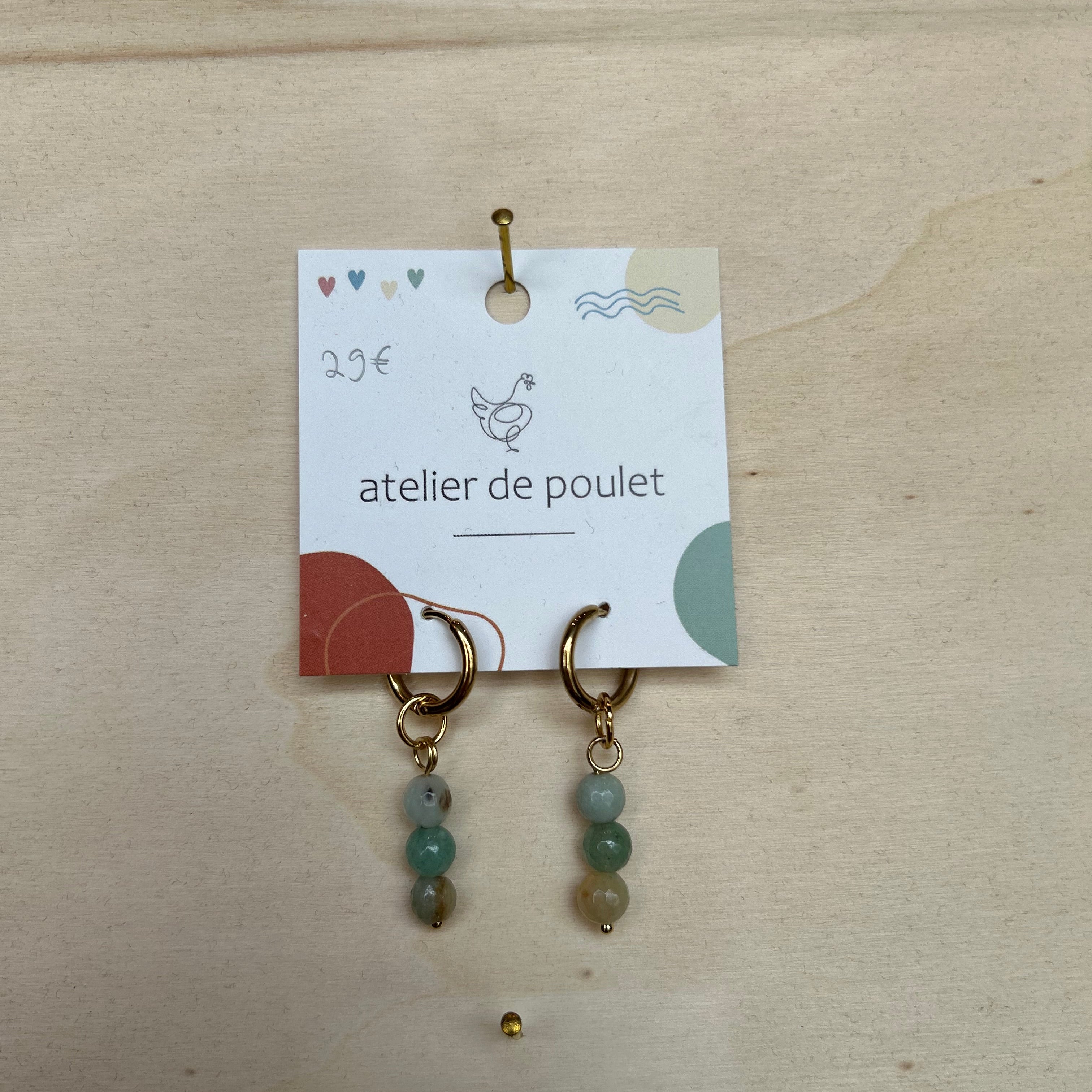 „Handgemachte Ohrringe von atelier de poulet – aus Edelsteinen in der Farbe Türkis, präsentiert auf Holzdisplay. Stilvolle Damen-Ohrringe als individueller Modeschmuck, ideal als Geschenk oder Accessoire