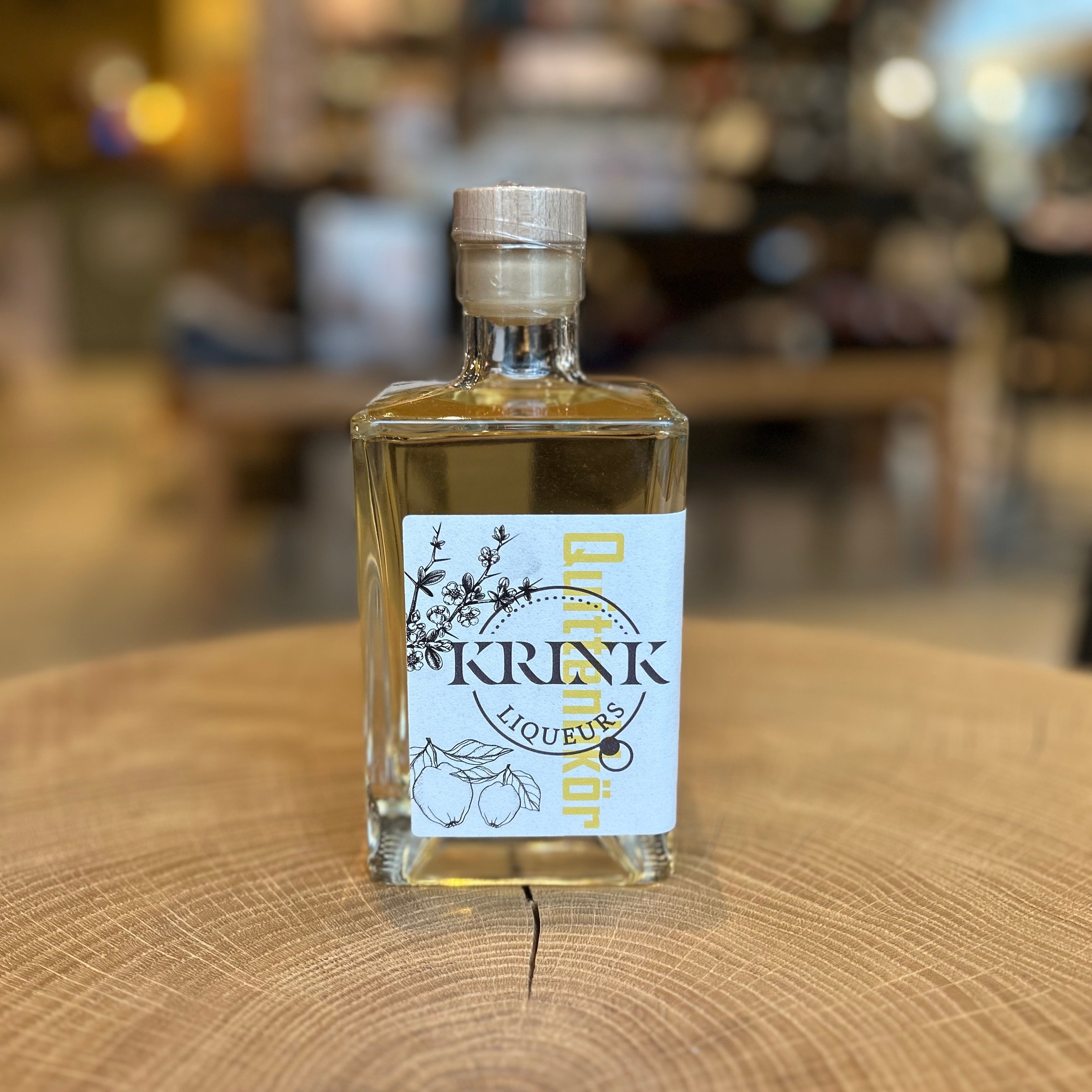 Quittenlikör in dekorativer Glasflasche von KREK Liqueurs auf Holzuntergrund – handgemachter Likör aus Quitten, hochwertiger Genuss, regionale Spirituose, Geschenkidee für Feinschmecker.
