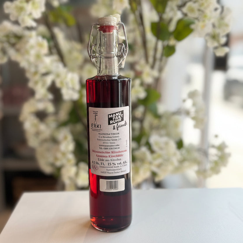 Rüttenscheider „Kirschtraum“ Kirschlikör in Glasflasche mit Bügelverschluss, Rückseite der Flasche vor unscharfem Hintergrund – handgemachter Kirschlikör aus Kirschen als Spirituosen-Spezialität.