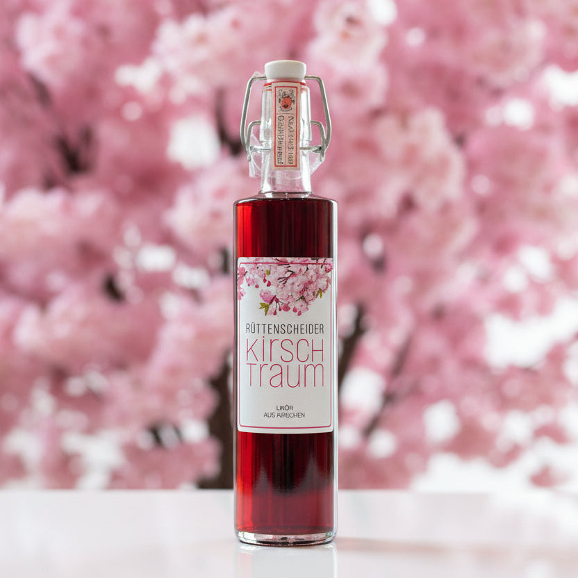Rüttenscheider „Kirschtraum“ Kirschlikör in Glasflasche mit Bügelverschluss, vor unscharfem Hintergrund – handgemachter Kirschlikör aus Kirschen als Spirituosen-Spezialität.