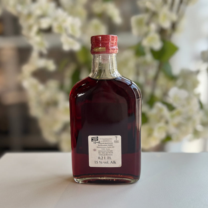 Rüttenscheider „Kirschtraum“ Kirschlikör in Glasflasche in klein, in der Hand gehalten vor unscharfem Hintergrund – handgemachter Kirschlikör aus Kirschen als Spirituosen-Spezialität.