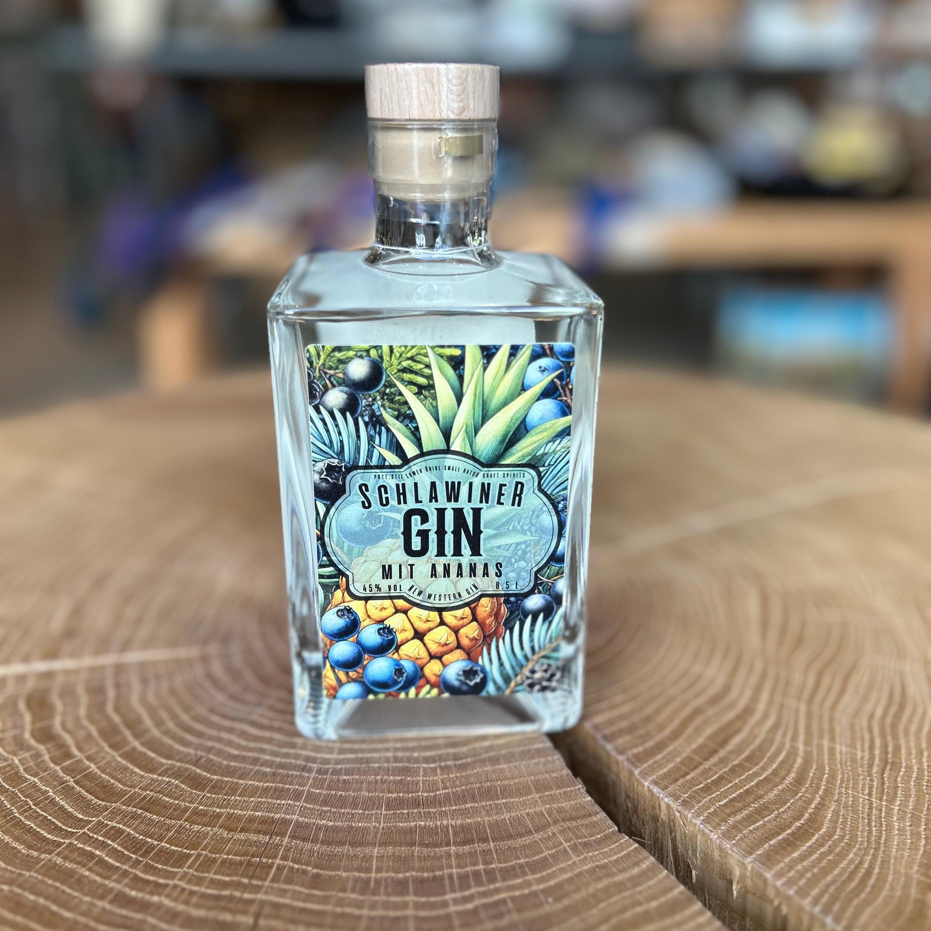 Schlawiner Gin mit Ananas in quadratischer Glasflasche, 45% Vol – fruchtiger Premium Gin aus Deutschland mit exotischem Ananasaroma, edel präsentiert auf Holztisch.