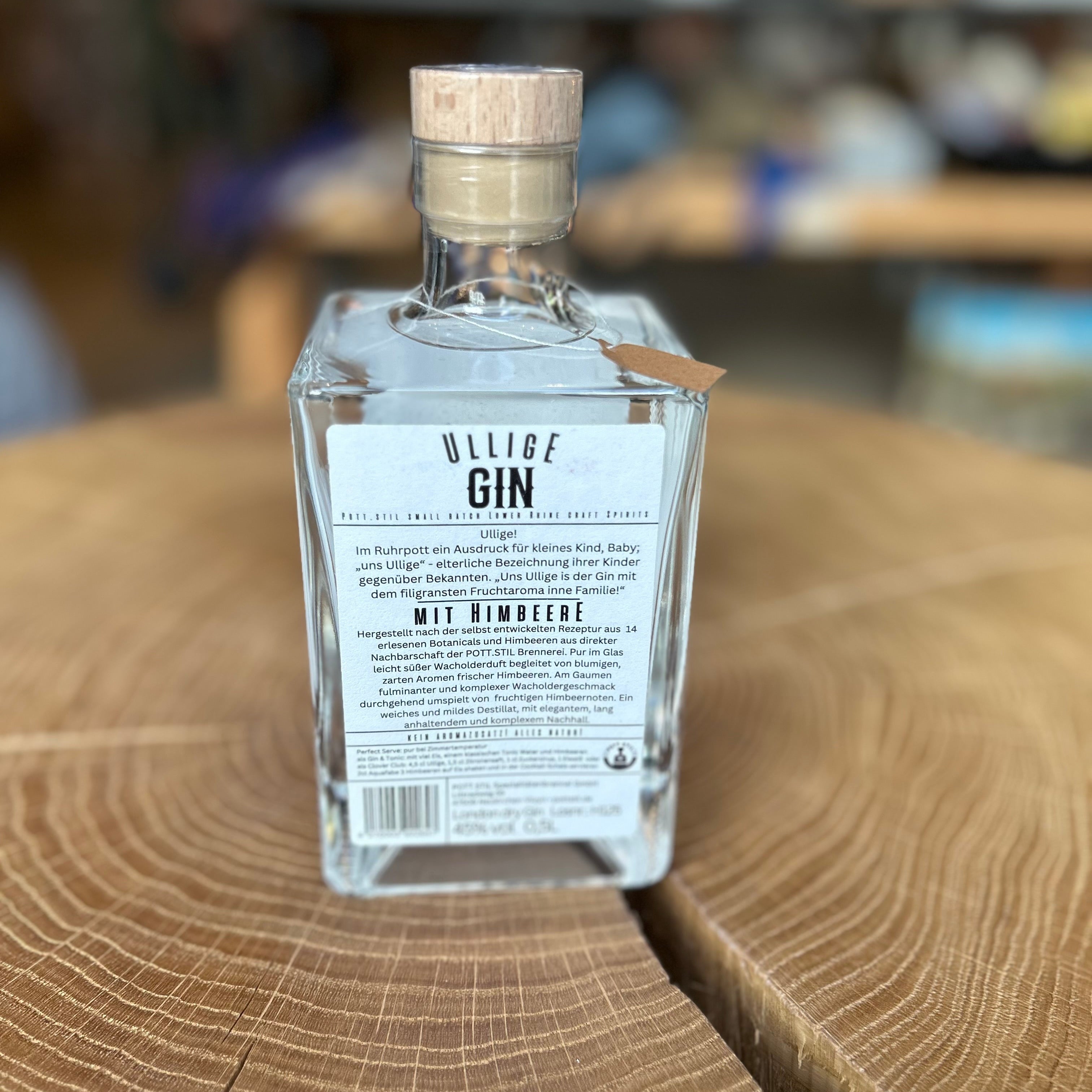 Ullig Gin mit Himbeere in quadratischer Glasflasche Rückseite, 45% Vol – fruchtiger Premium Gin aus Deutschland mit intensivem Himbeeraroma, edel präsentiert auf Holztisch.