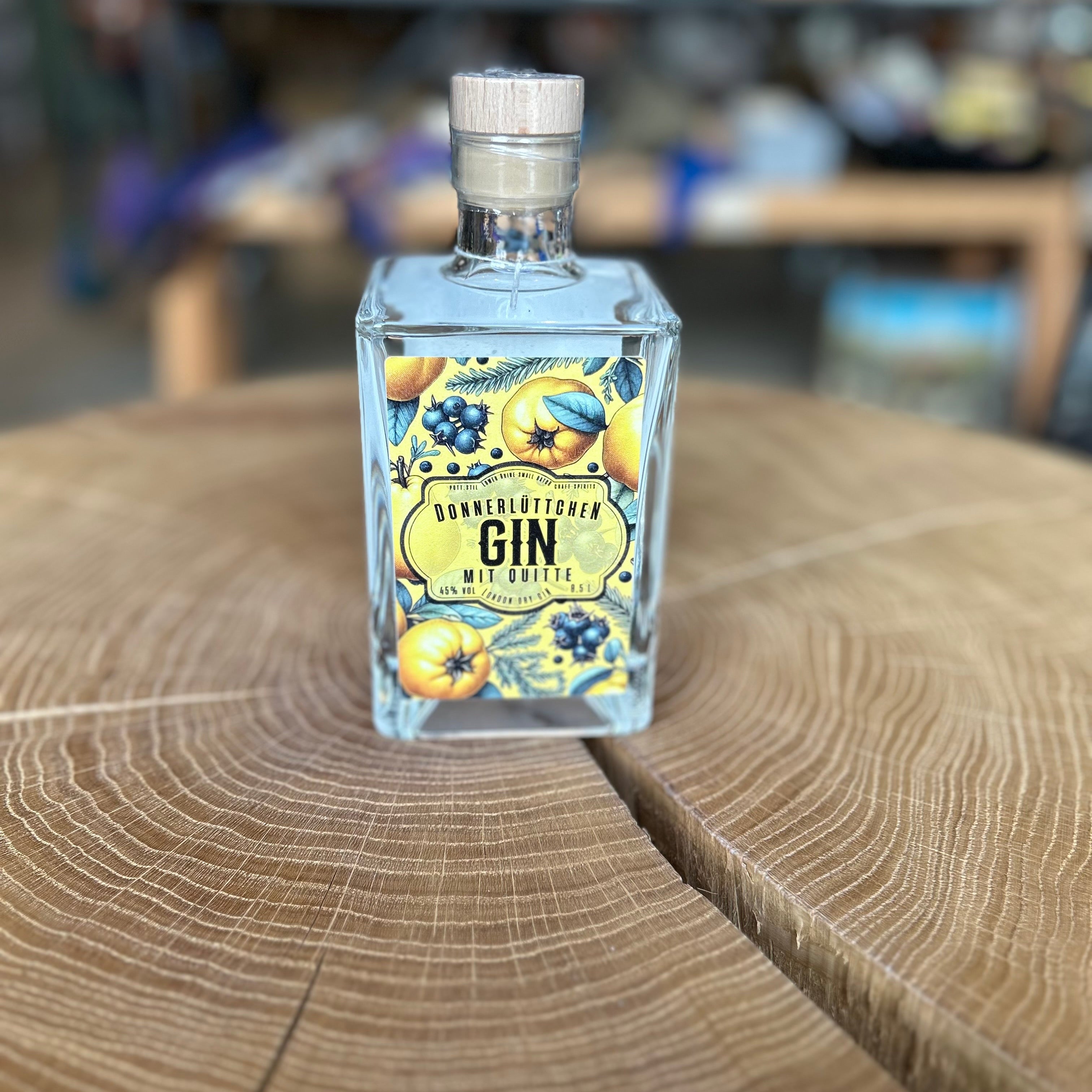 Donnerlüttchen Gin mit Quitte in quadratischer Glasflasche, 45% Vol – Premium deutscher Gin mit fruchtig-herbem Aroma, stilvoll präsentiert auf Holztisch.
