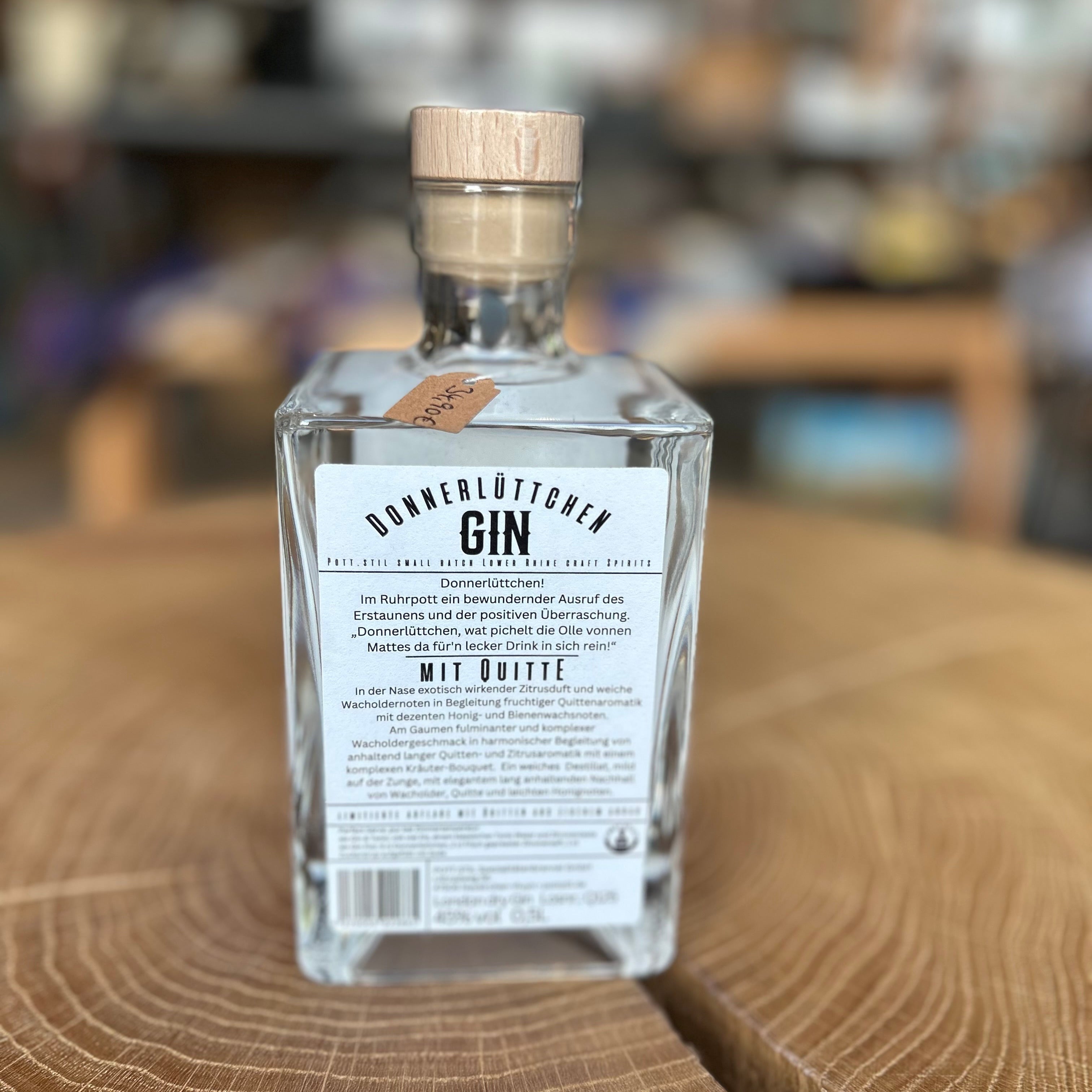 Donnerlüttchen Gin mit Quitte in quadratischer Glasflasche Rückseite, 45% Vol – Premium deutscher Gin mit fruchtig-herbem Aroma, stilvoll präsentiert auf Holztisch.