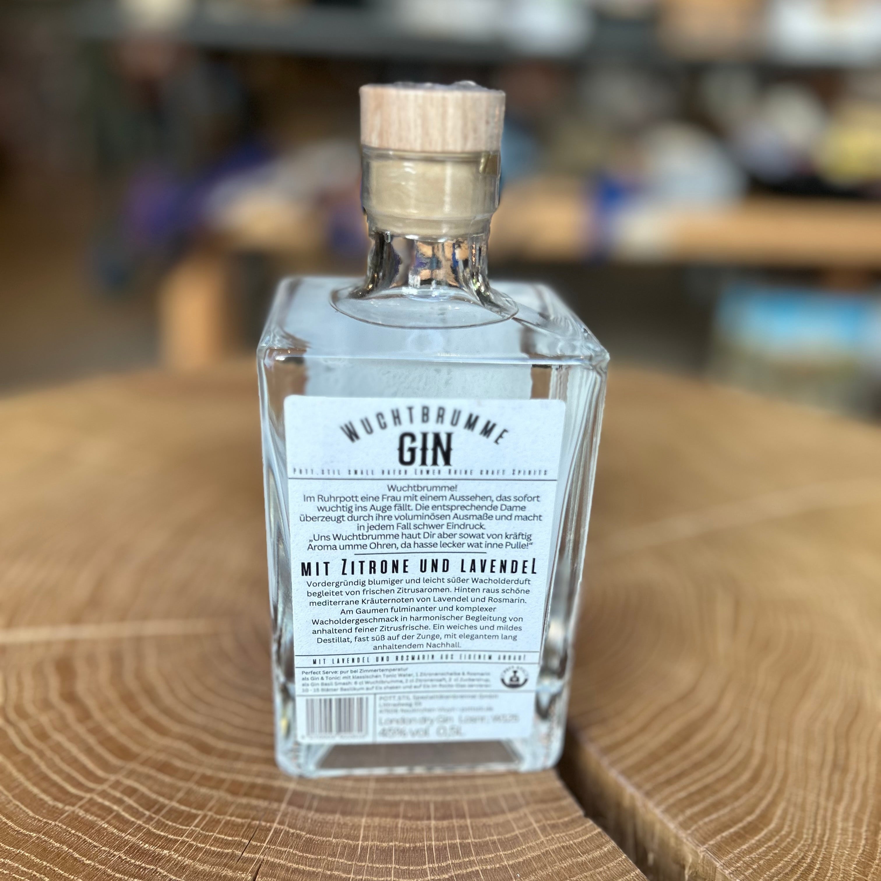 Wuchtbrumme Gin Zitrone Lavendel in quadratischer Glasflasche Rückseite, 45% Vol – aromatischer Premium Gin mit frischer Zitrone und feinem Lavendel, präsentiert auf Holztisch.
