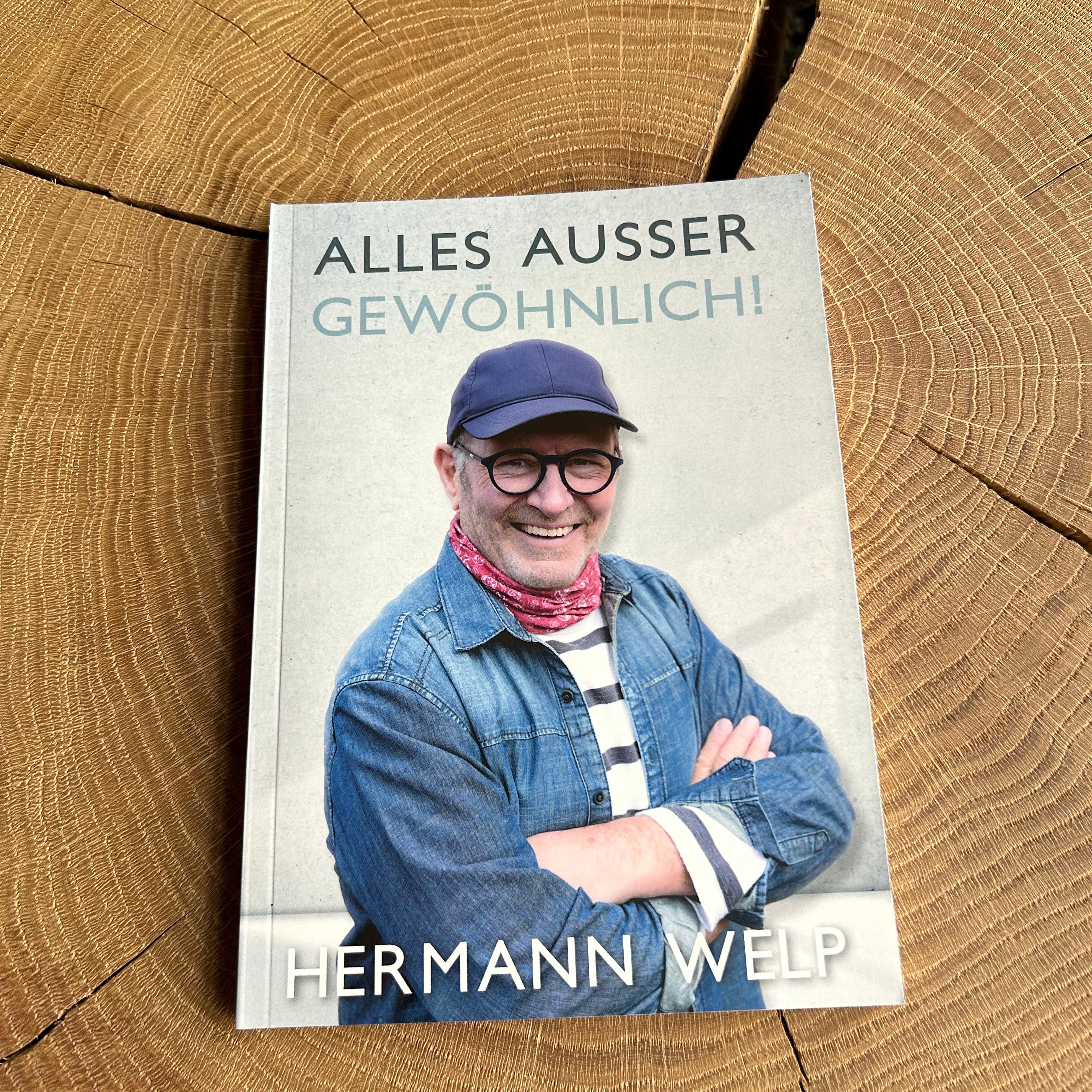 Buch Alles Ausser Gewöhnlich von Hermann Welp, liegt auf einem Holztisch