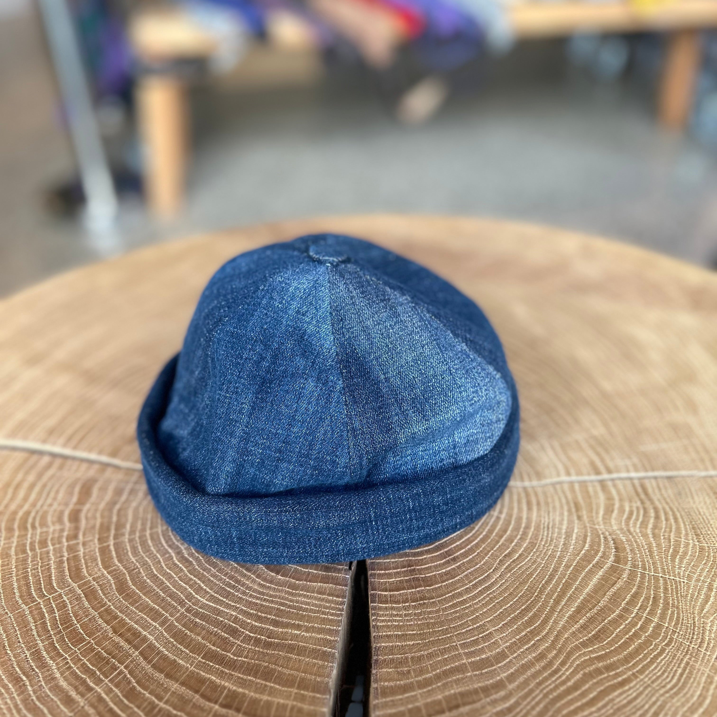 Fischermütze in der Farbe Dunkel Jeans, liegt auf einem Holztisch