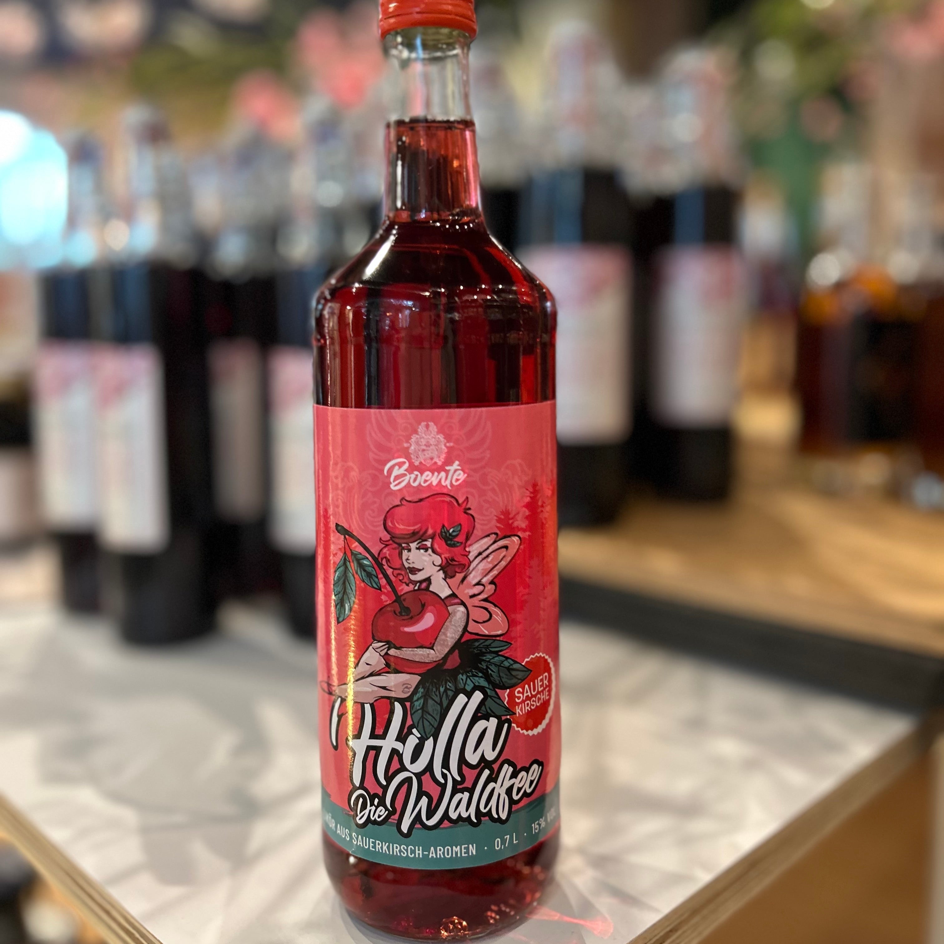 Holla die Waldfee Sauerkirsch Likör 15% Vol in 0,7l Flasche von Boente – fruchtiger Likör mit intensivem Sauerkirsch-Aroma, ideal zum Mixen von Cocktails oder als Geschenk, präsentiert im Regal.