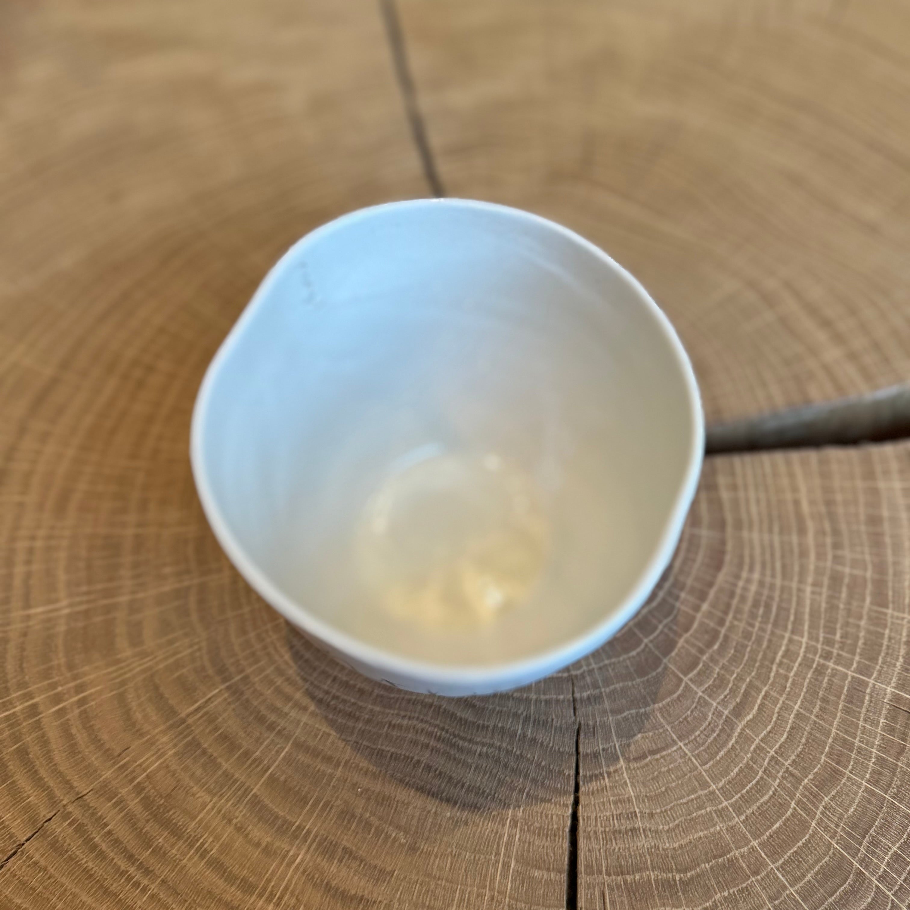 Handgefertigte Keramikschale „Ruhrpottkind“ von Manufaktur Peng, kleine weiße Bowl mit handgeschriebener Schrift und Smiley, minimalistisches Design, Unikat aus Keramik auf Holzoberfläche.