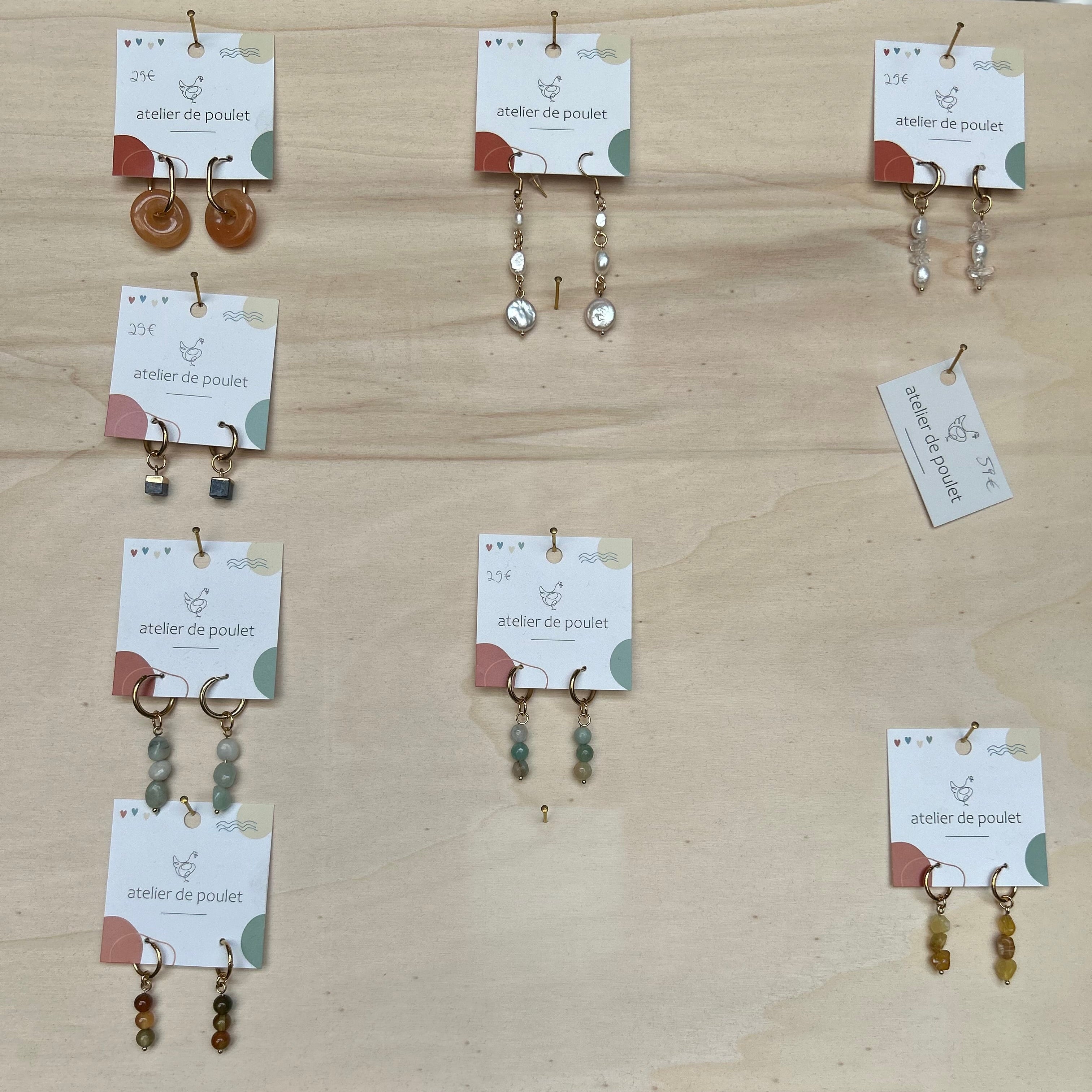 „Handgemachte Ohrringe von atelier de poulet – verschiedene Modelle mit Perlen, Edelsteinen und Schmuckelementen, präsentiert auf Holzdisplay. Stilvolle Damen-Ohrringe als individueller Modeschmuck, ideal als Geschenk oder Accessoire