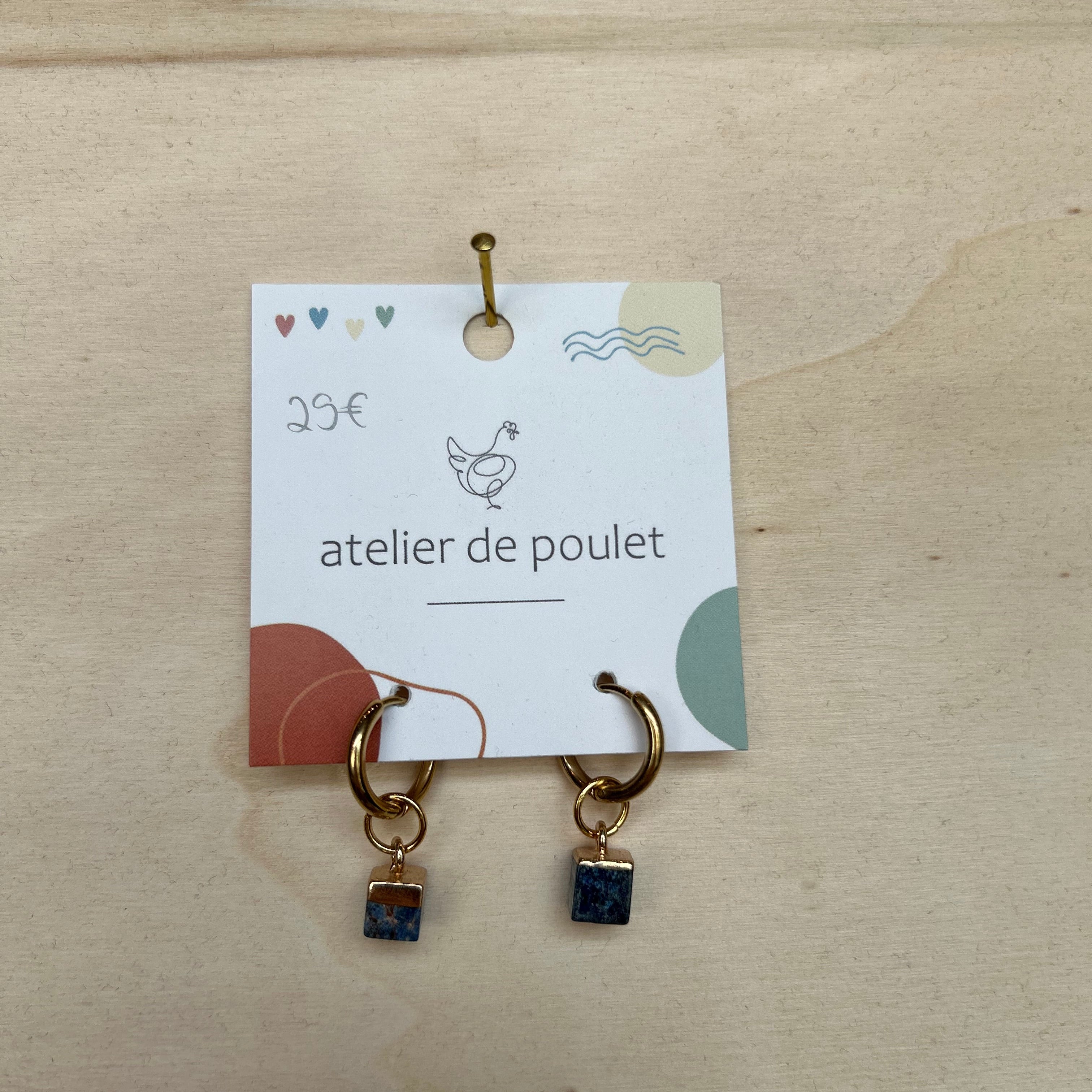 Handgemachte Ohrringe von atelier de poulet –  mit  Edelsteinenin der Farbe Blau und Schmuckelementen, präsentiert auf Holzdisplay. Stilvolle Damen-Ohrringe als individueller Modeschmuck, ideal als Geschenk oder Accessoire