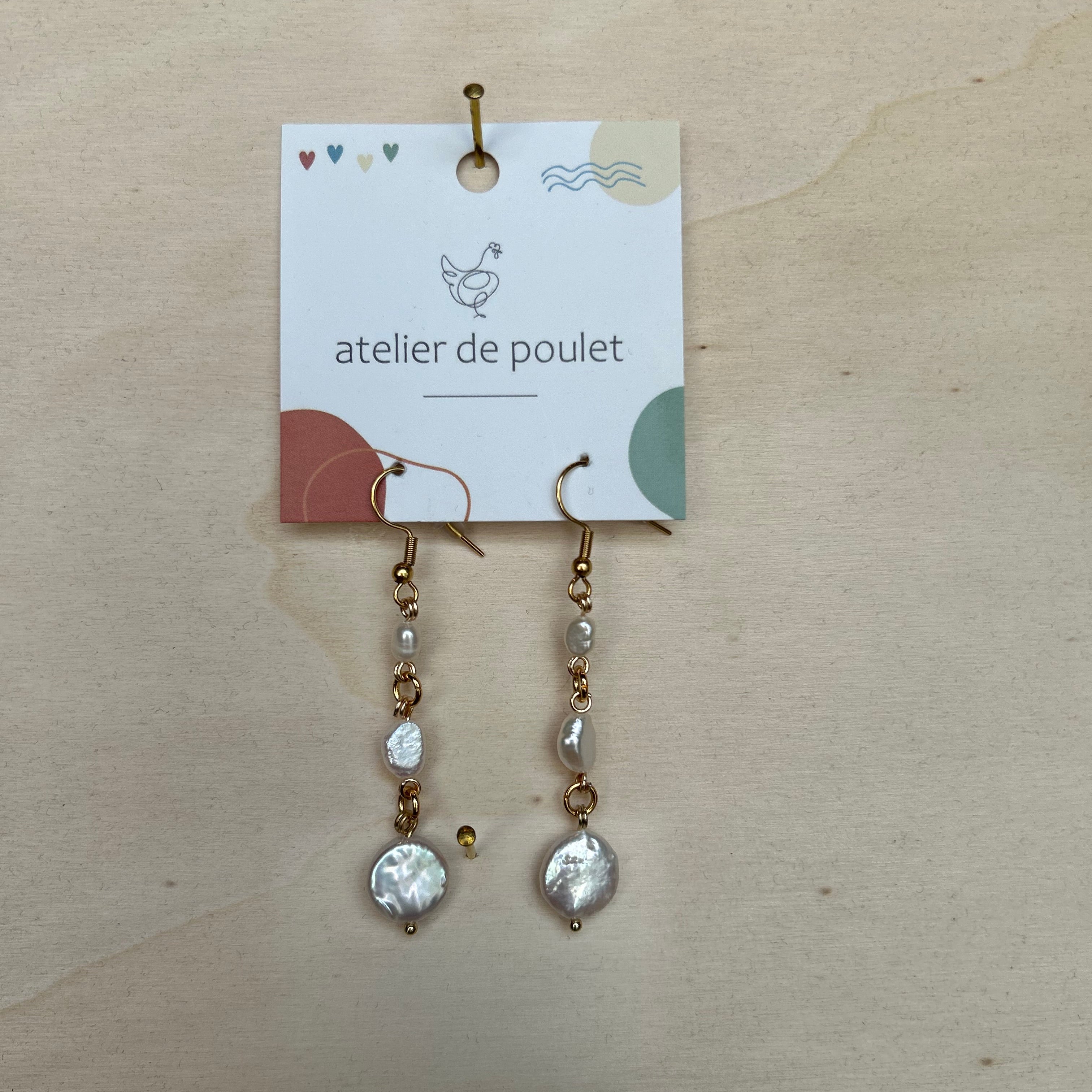 „Handgemachte Ohrringe von atelier de poulet – aus Perlen in der Farbe Weiß, präsentiert auf Holzdisplay. Stilvolle Damen-Ohrringe als individueller Modeschmuck, ideal als Geschenk oder Accessoire