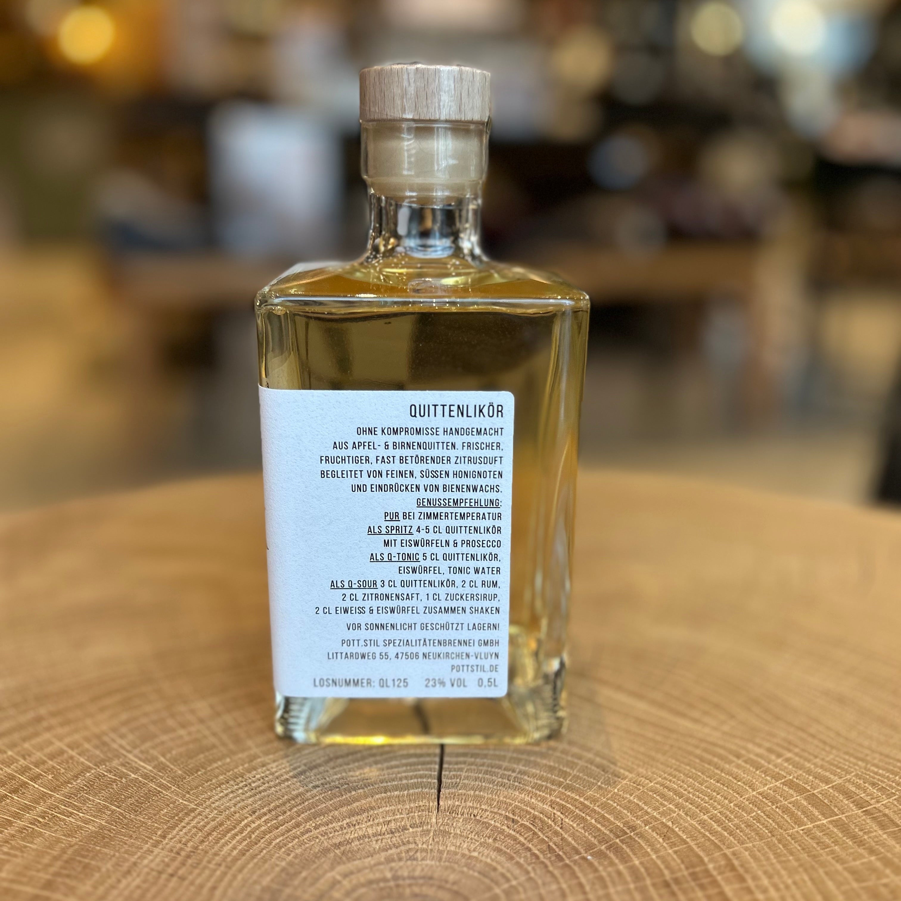 Quittenlikör in dekorativer Glasflasche von KREK Liqueurs auf Holzuntergrund – handgemachter Likör aus Quitten, hochwertiger Genuss, regionale Spirituose, Geschenkidee für Feinschmecker.
