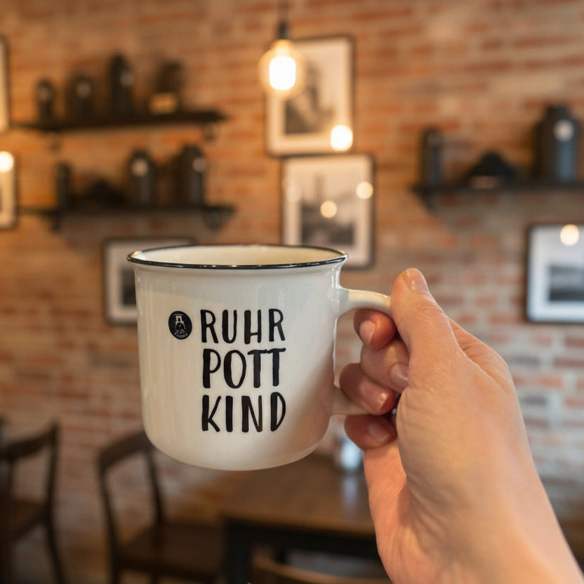Weiße Keramiktasse mit Aufdruck „Ruhrpott Kind“ in der Hand gehalten – Ruhrgebiet Tasse als Geschenk für Ruhrpott-Fans, Kaffeetasse mit regionalem Ruhrgebiet Design.